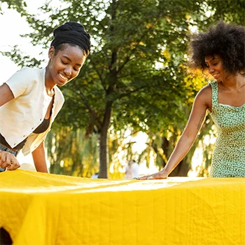 Two women outside putting a table cover on a table