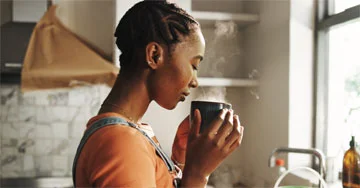 An image of a woman about to enjoy a mug of coffee.