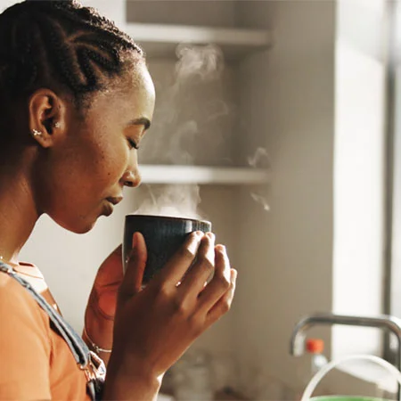 An image of a woman about to enjoy a mug of coffee.