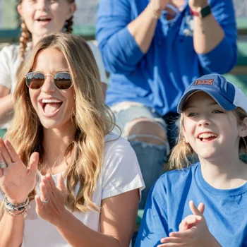 A woman and a girl in a baseball hat in a stadium cheering