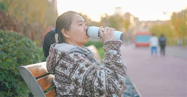 person sitting on a bench drinking out of a water bottle