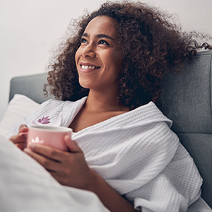 Woman drinking coffee in a blanket