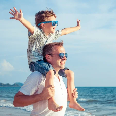 Son on his father’s shoulders while spending time at the beach.