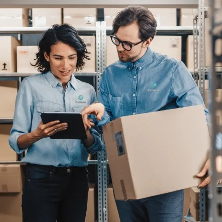 Two warehouse workers looking at an inventory list.
