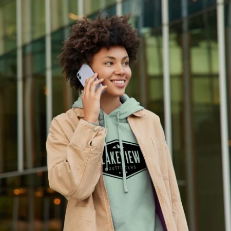 Smiling person on their phone outside a city center.