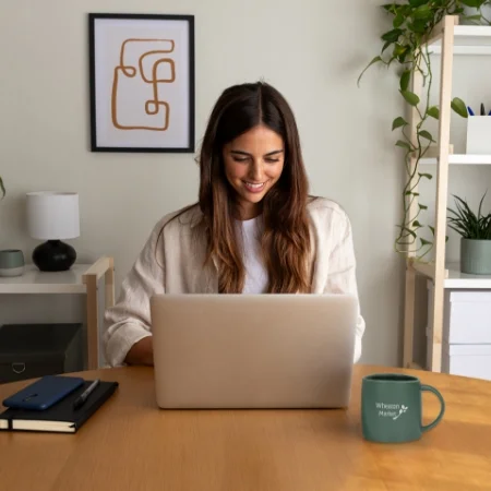 Smiling person on laptop in home office.