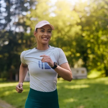 Smiling jogger wearing a matching branded athletic shirt and visor.