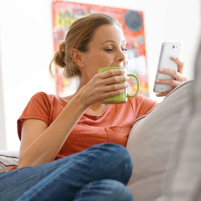 Woman sitting enjoying coffee with her phone