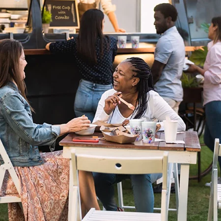 Two women eating food at a food truck