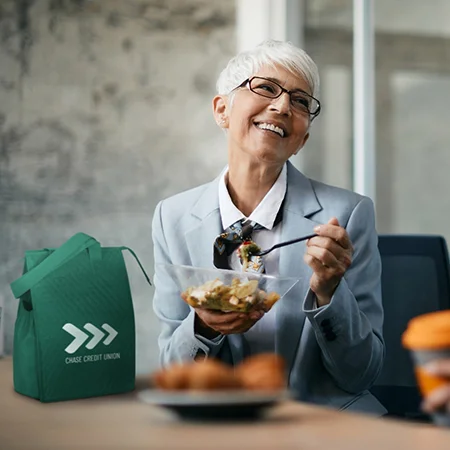 Woman at desk eating lunch with a resuable lunch cooler