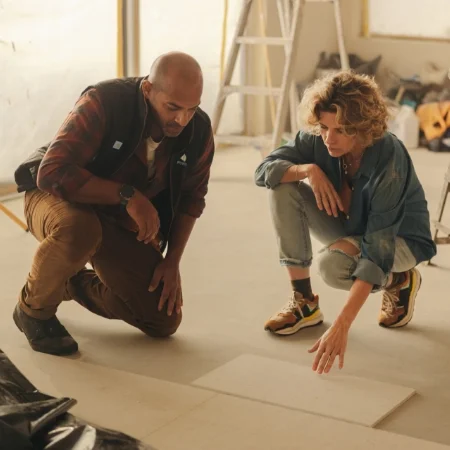Two people working on a wood floor wearing Carhartt branded products