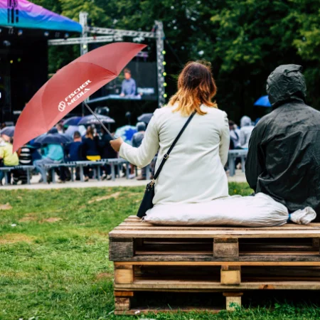 A man and woman sitting on a bench with an umbrella