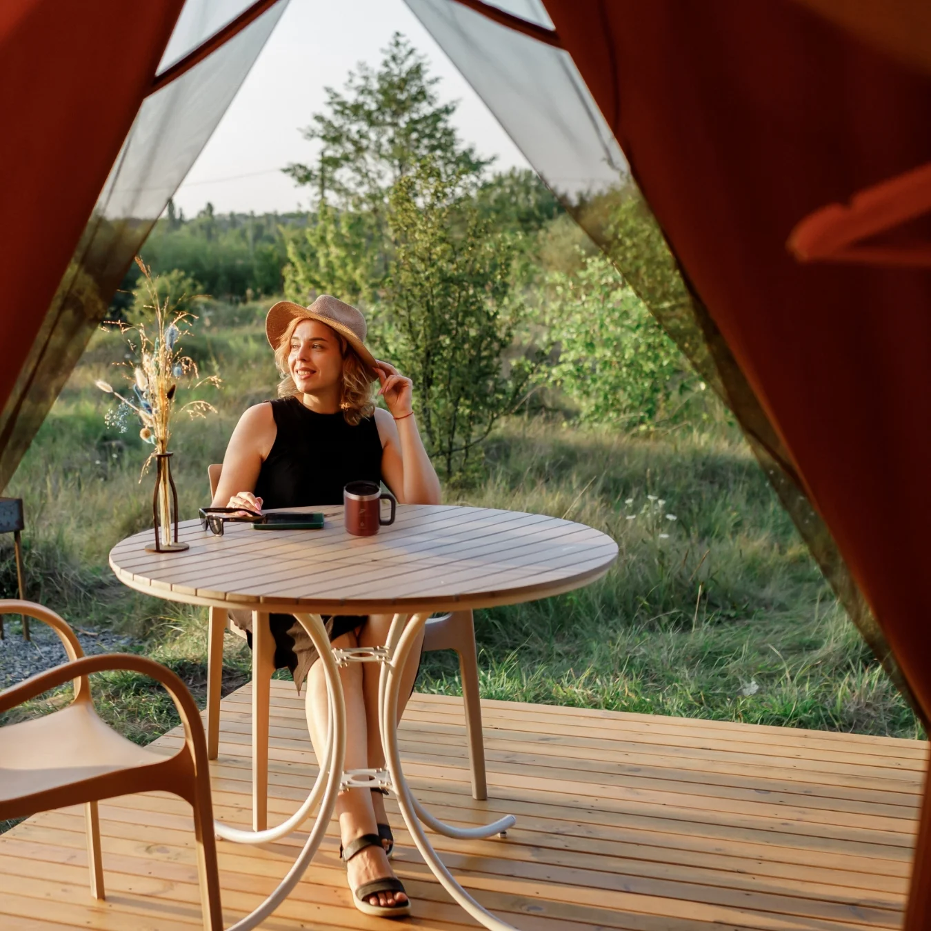 Smiling person sitting outdoors on a glamping tent porch.