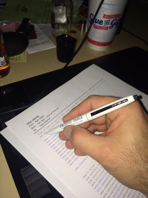 a hand holding a pen over a piece of paper