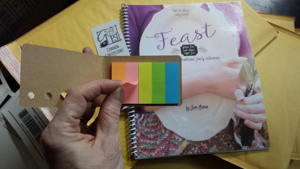 a hand holding a book with colorful sticky notes