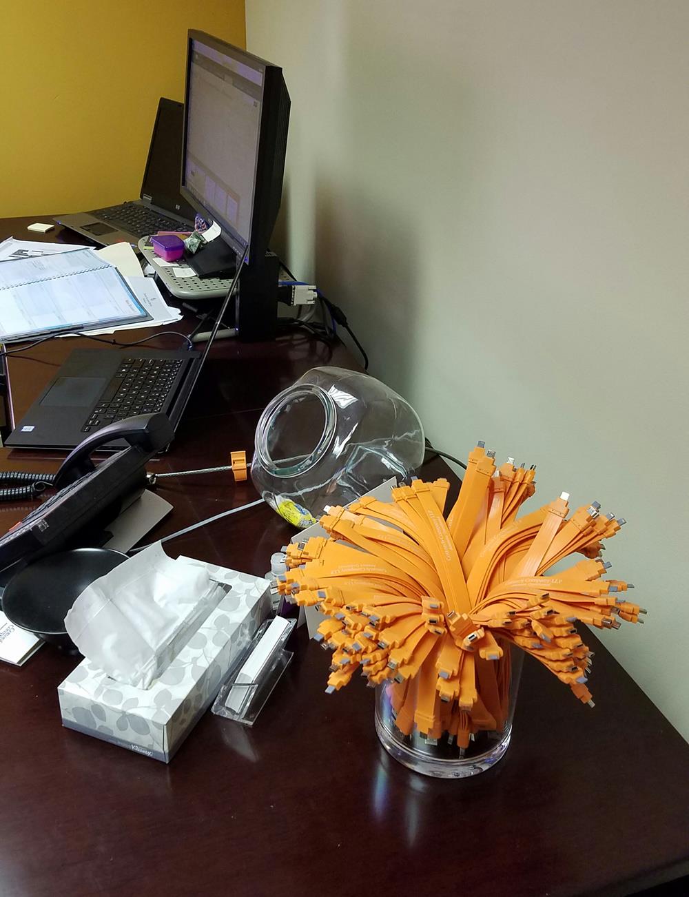 a bunch of orange cables in a glass on a desk