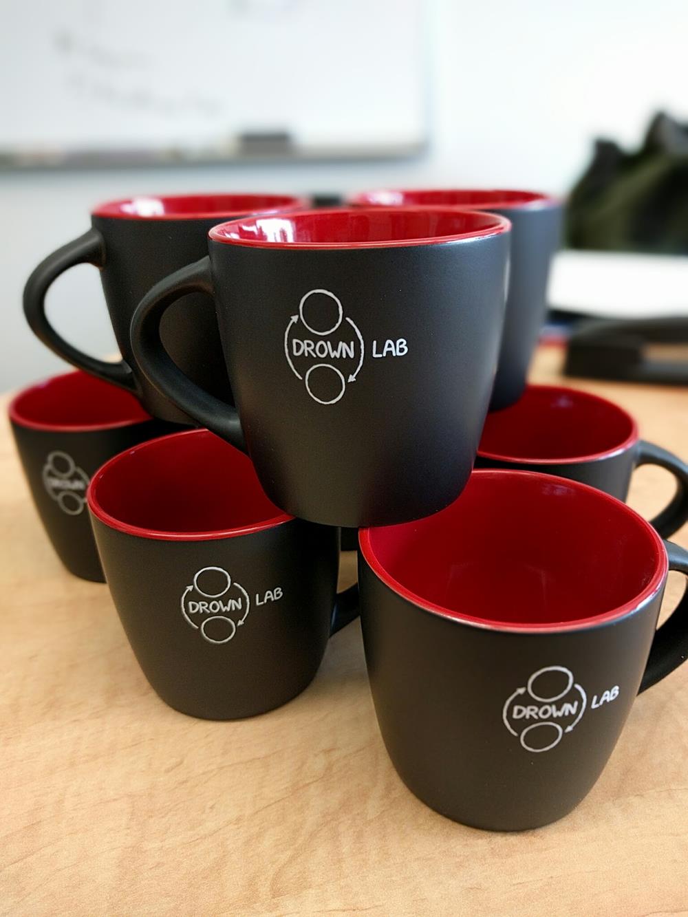 a group of black and red coffee mugs