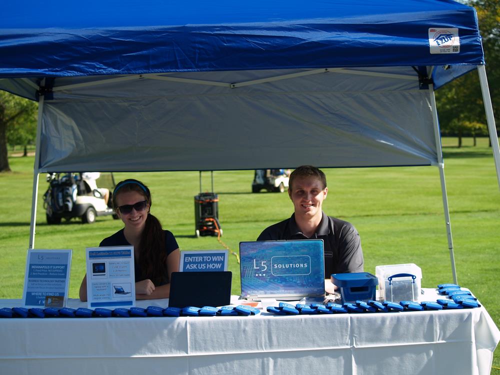 Customer photo from Miranda of our Can Kooler with Bottle Opener, a man and woman at a booth