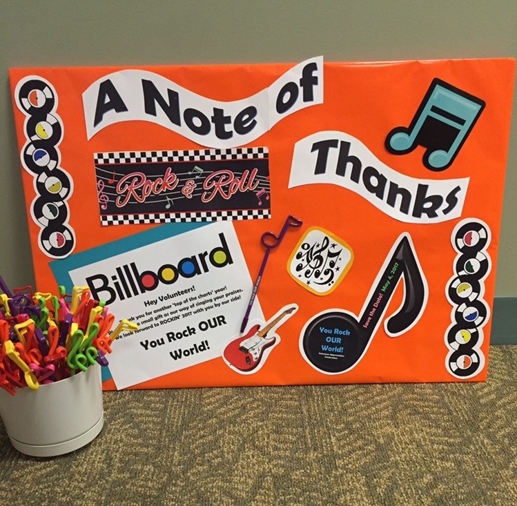 an orange board with stickers and a bucket of pens