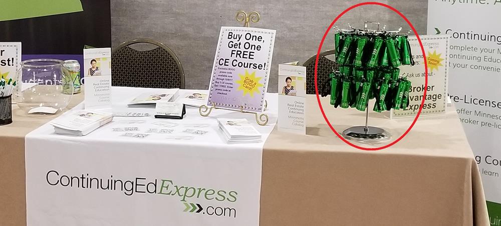 Customer photo from Rhea of our Pocket LED Flashlight, a table with a sign and a table with green cans on it