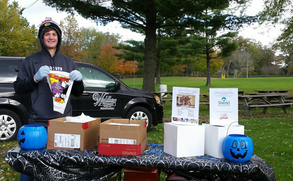 a person standing next to a table with boxes and a black car