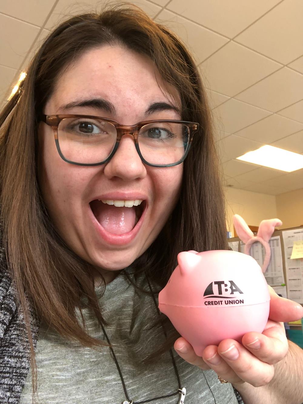 Customer photo from Rachel of our Pig Stress Reliever, a woman holding a piggy bank