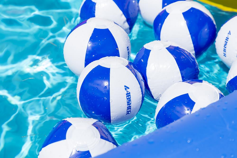 a group of beach balls floating in a pool