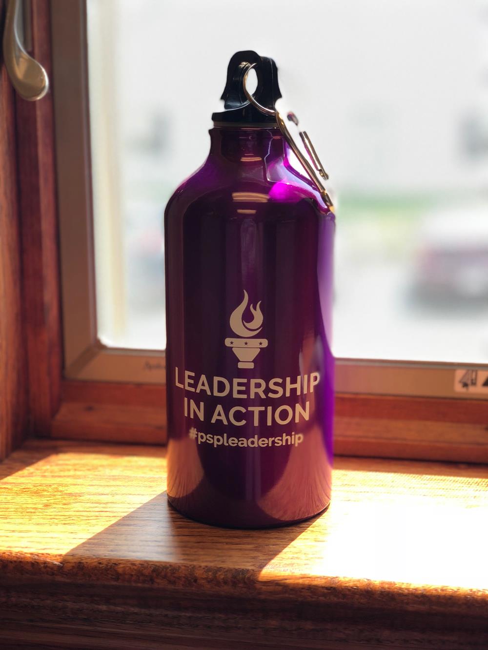 Customer photo from Kasi of our Lil' Shorty Aluminum Sport Bottle - 17 oz., a purple water bottle on a window sill
