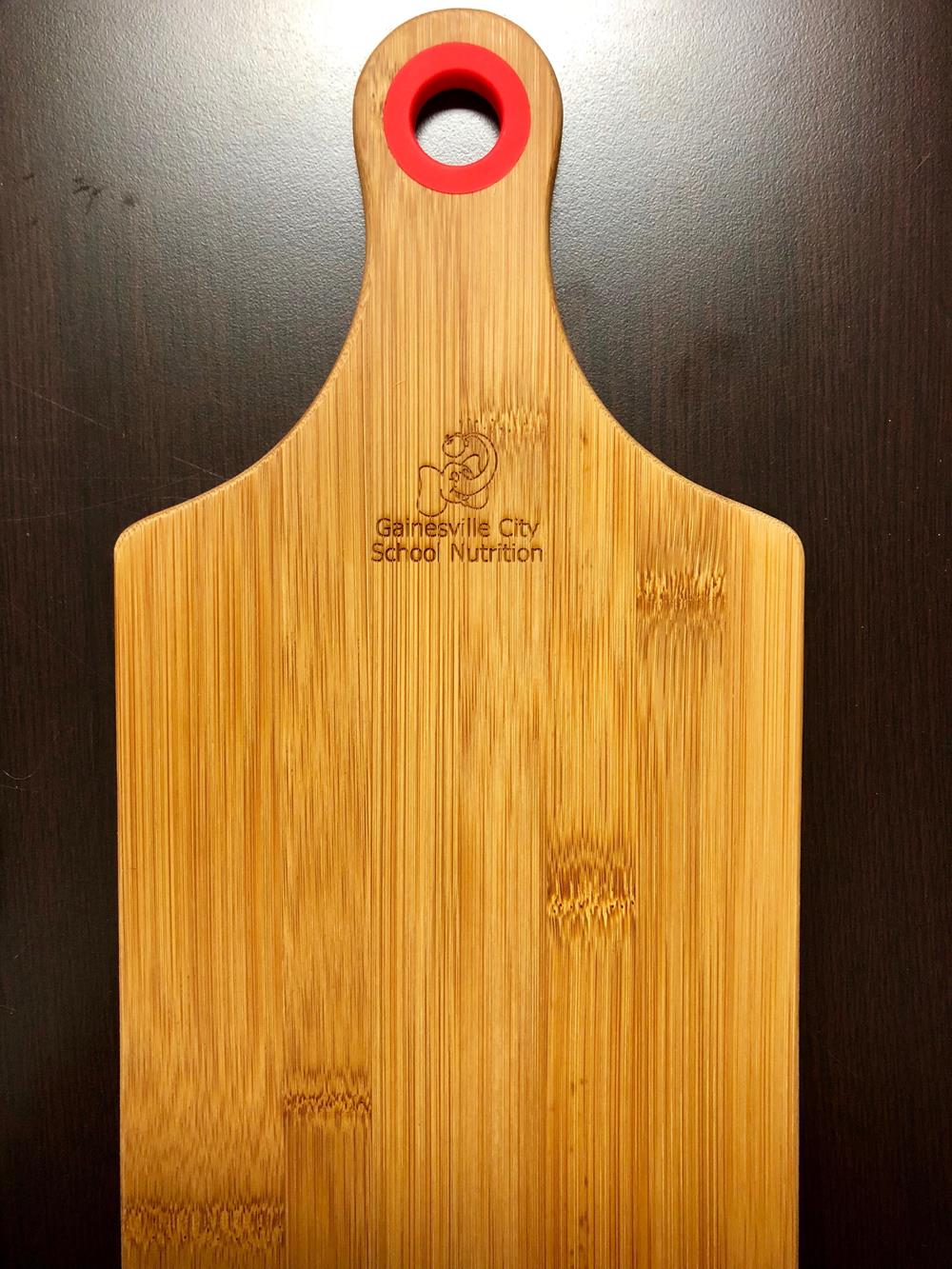 a wooden cutting board with a red handle