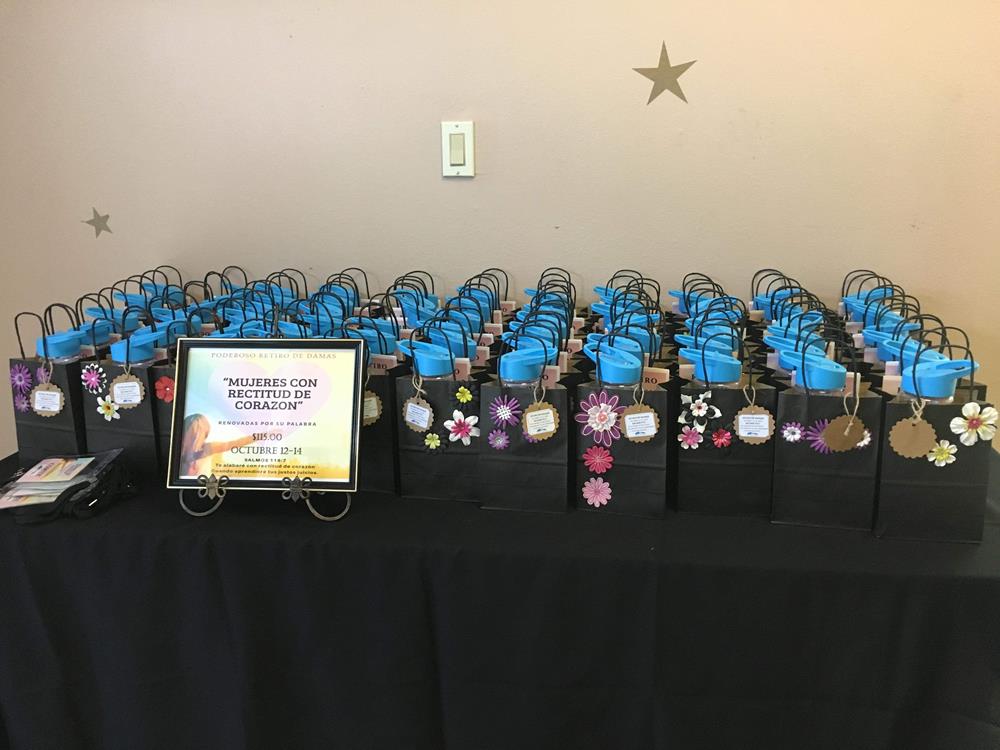 Customer photo from Marielitos of our Clear Impact Halcyon Water Bottle with Flip Straw Lid - 24 oz, a table with many bags of gift