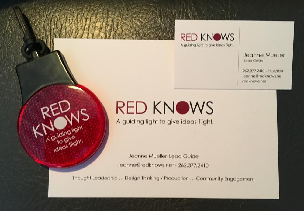 a red badge on a black strap next to a business card