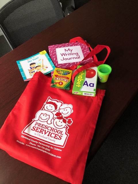 Customer photo from Tina of our Cotton Sheeting Colored Economy Tote - 12-1/2" x 12", a red bag with books and a red bag on a table