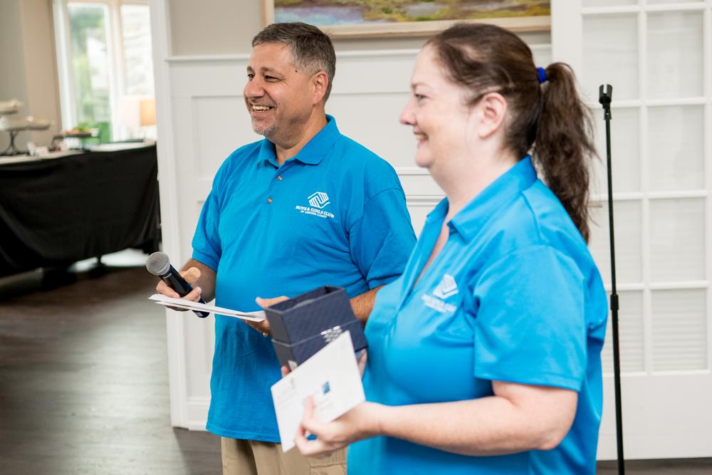 a man and woman in blue shirts holding a microphone and a box