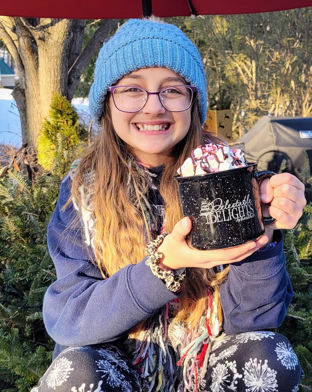 Customer photo from Heather of our Campfire Ceramic Mug - Colors - 15 oz., a girl holding a mug with marshmallows