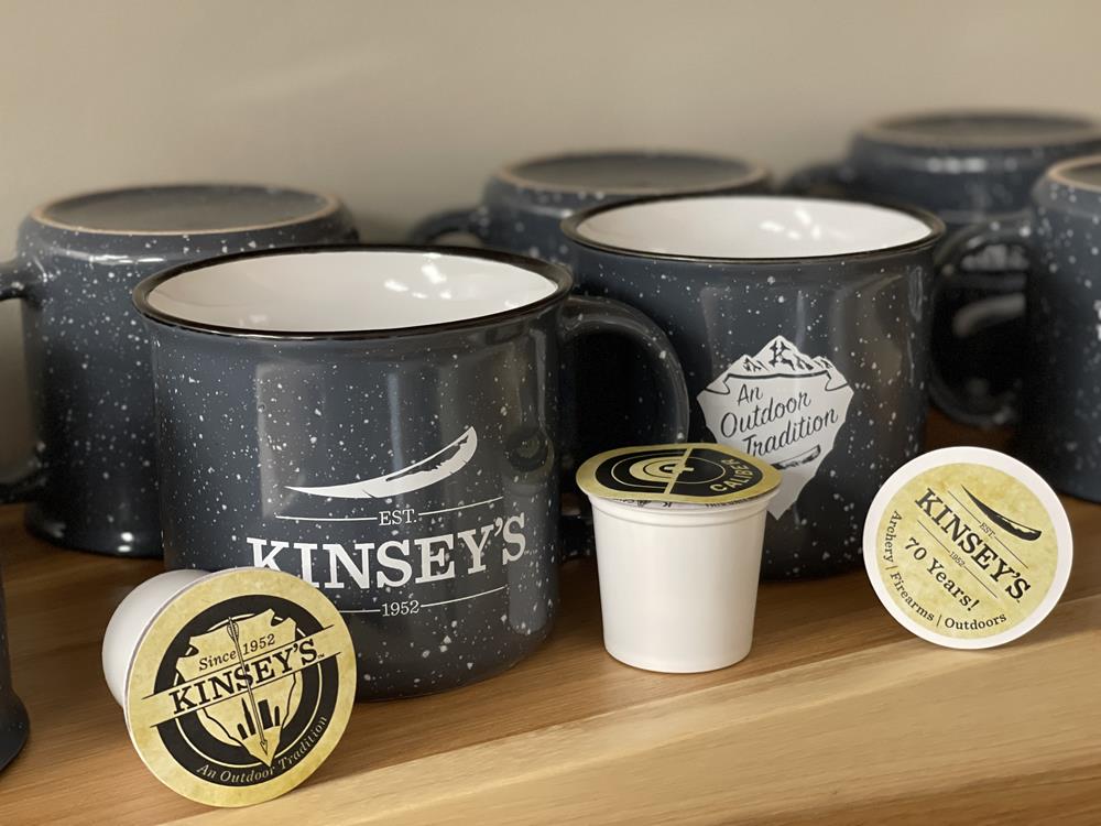 Customer photo from Nathaniel of our Campfire Ceramic Mug - Colors - 15 oz., a group of coffee cups and capsules on a shelf