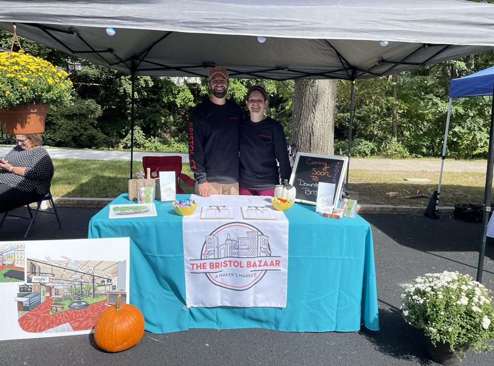 Customer photo from Carolyn of our Serged 6' Closed-Back Table Throw and Runner Kit, a man and woman standing under a tent