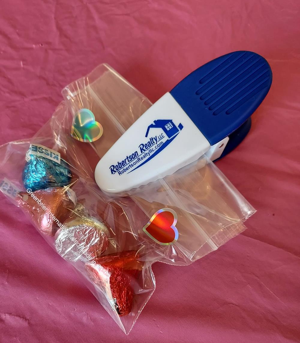 a white and blue stapler next to a bag of candy