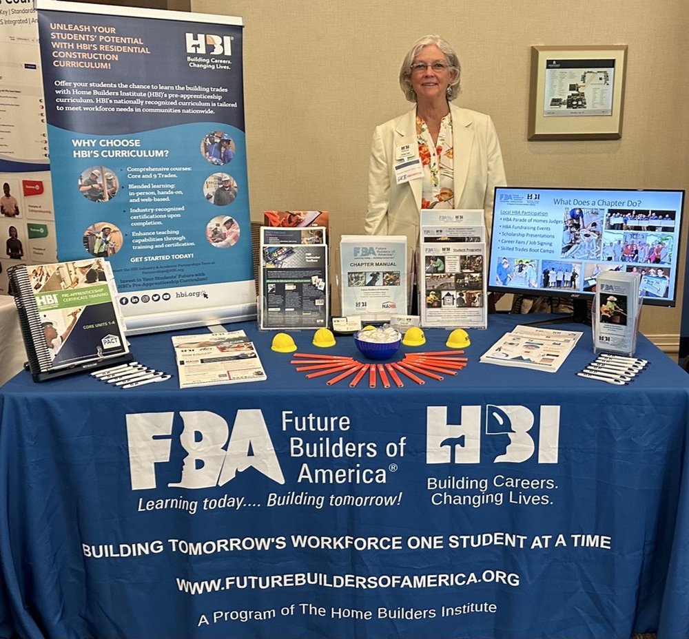 Customer photo from Melissa of our Economy Tabletop Retractable Banner Display - 24", a woman standing behind a table with a blue tablecloth