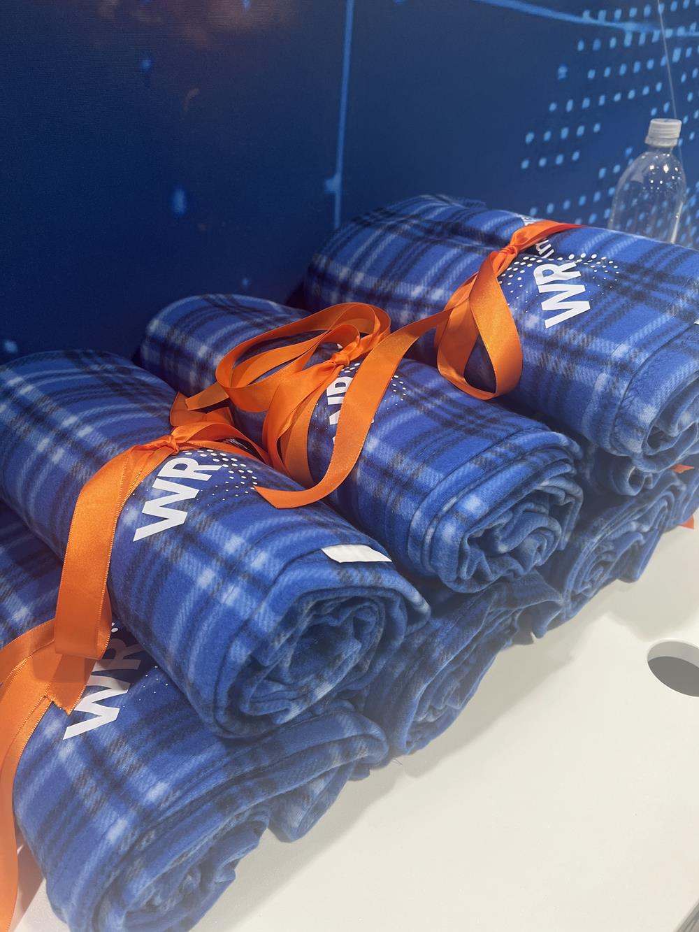 a stack of blue blankets with orange ribbons