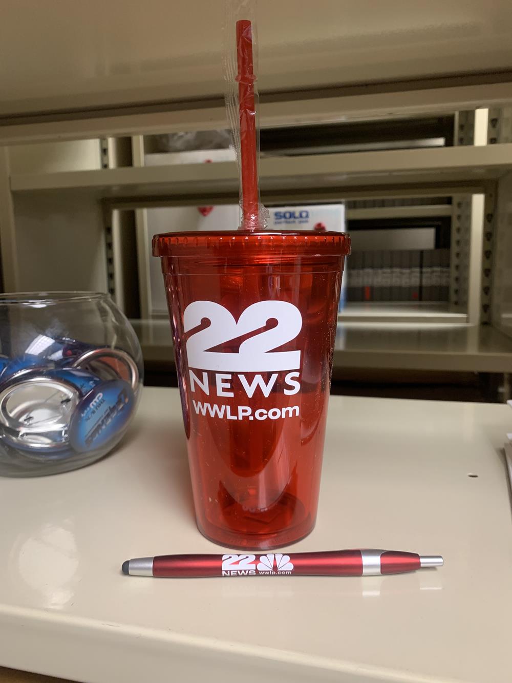 a red cup with a straw and a pen