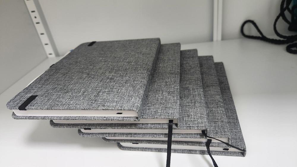 Customer photo from Eli of our Javelin Pen, a stack of notebooks on a table