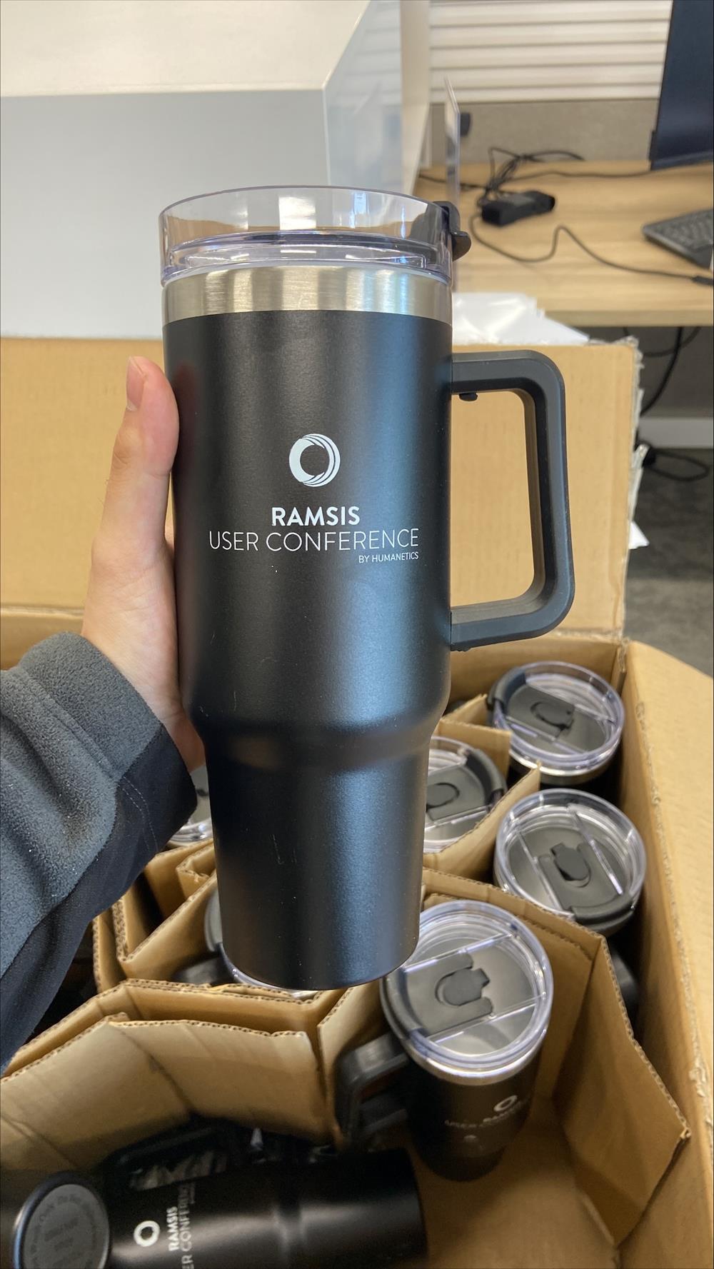 a hand holding a black and silver coffee mug