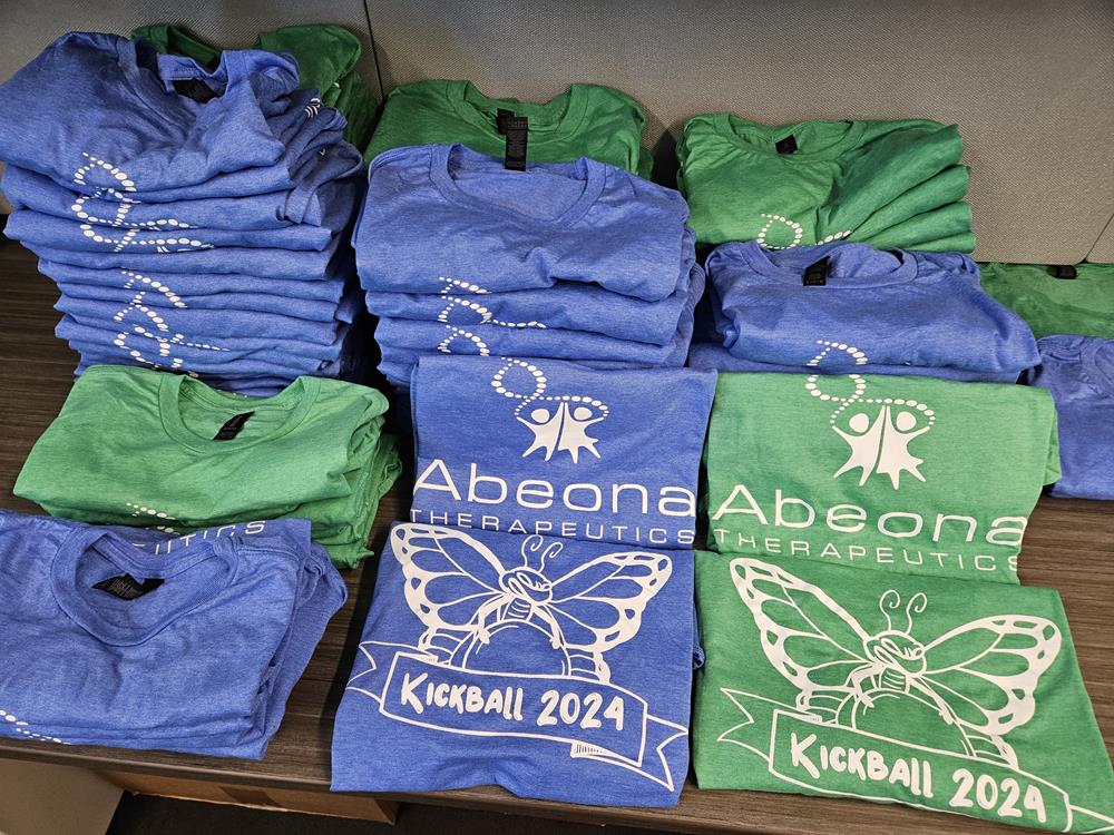 Customer photo from Julie of our Gildan Softstyle T-Shirt - Men's - Colors - Screen, a stack of t-shirts on a table