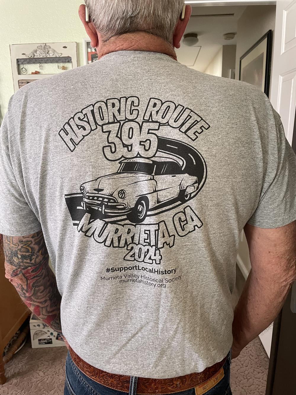 a man wearing a grey shirt with a car on it