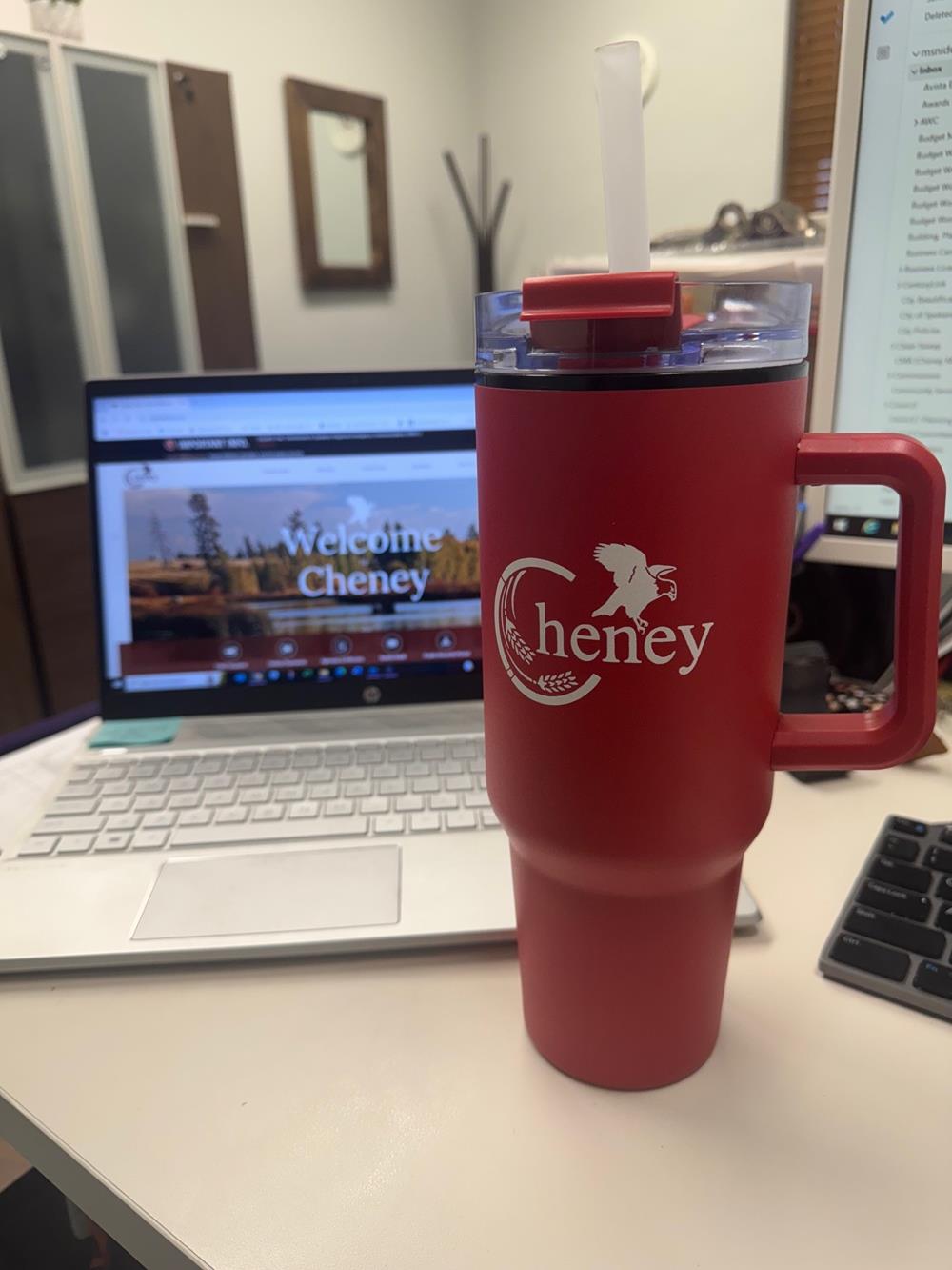 a red cup with straw in front of a laptop