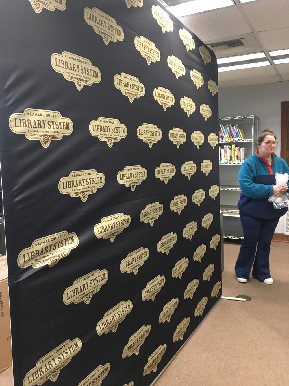 Customer photo from Brianna of our EuroFit Modular Straight Wall - 7-1/2' x 8', a woman standing next to a wall of books