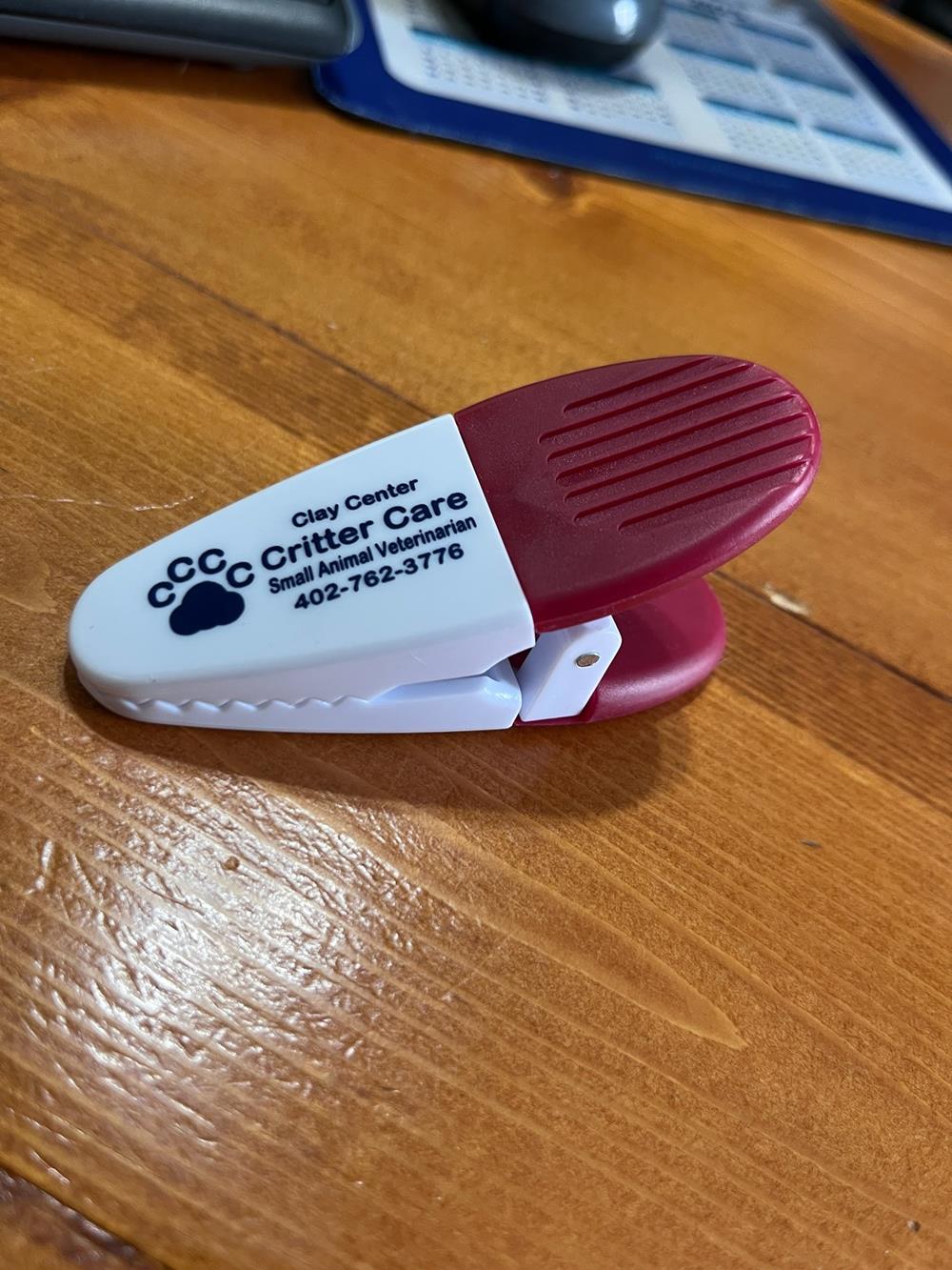 Customer photo from Susan of our Power Clip - Opaque, a small white and red clip on a wood surface