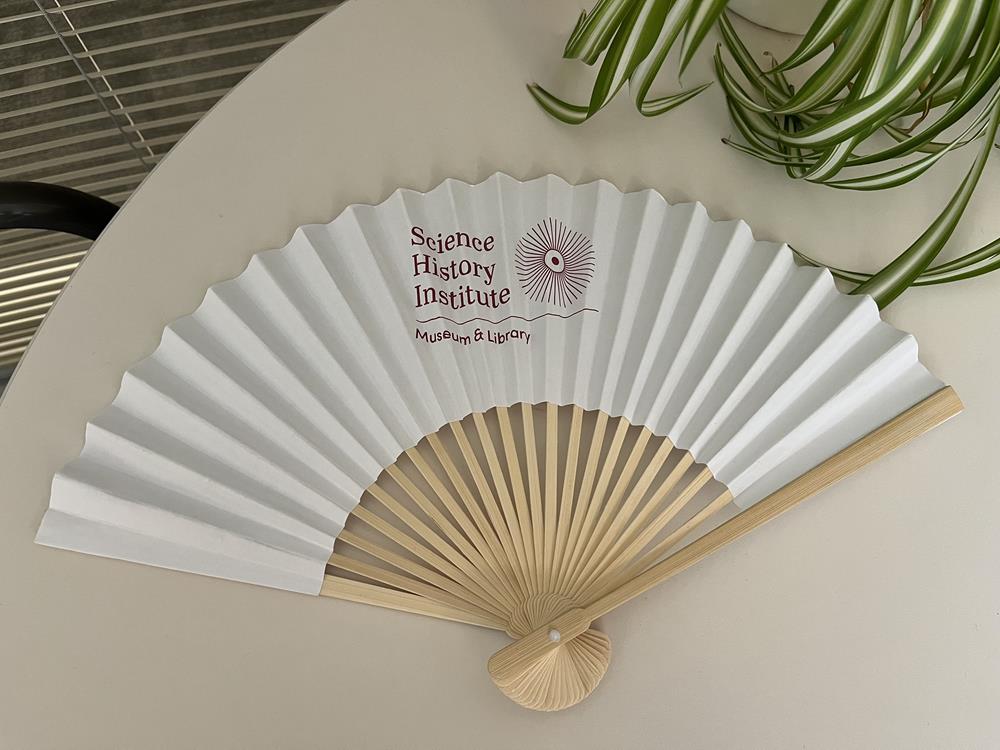 Customer photo from Charlotte of our Folding Hand Fan, a white fan on a table