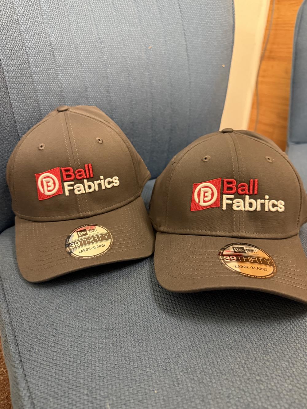 Customer photo from Ian of our New Era Structured Stretch Fit Cap - 3D Puff Embroidery, two hats on a chair