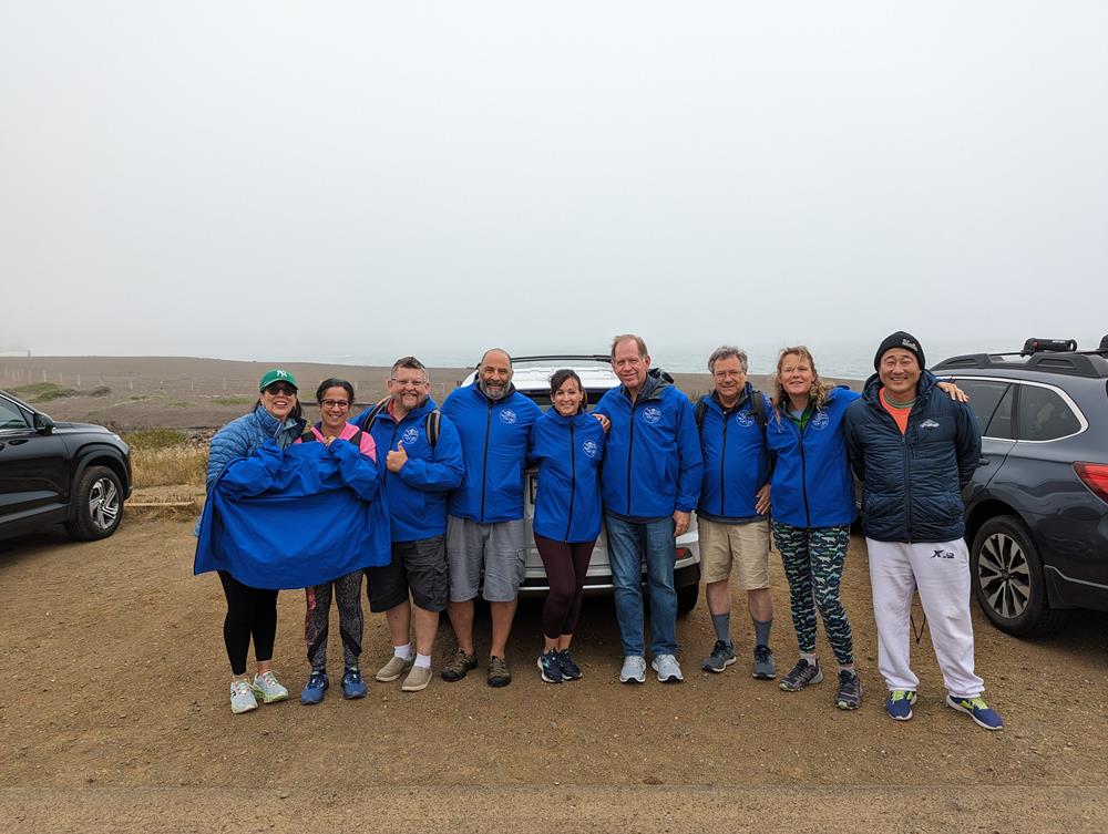 Customer photo from Michael of our Fleet Performance Pro LS  Hooded T-Shirt, a group of people in blue jackets standing in front of a car